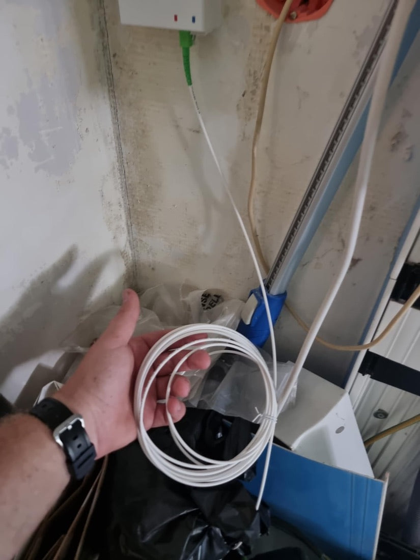 Câble fibre SpeedOptic 5 m tenu en main devant la prise fibre murale