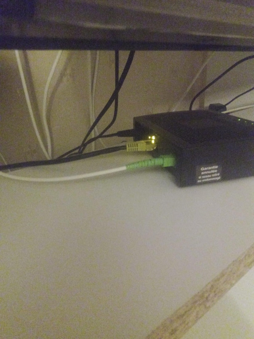 Câble fibre SpeedOptic à connecteur vert branché sur une box SFR 7